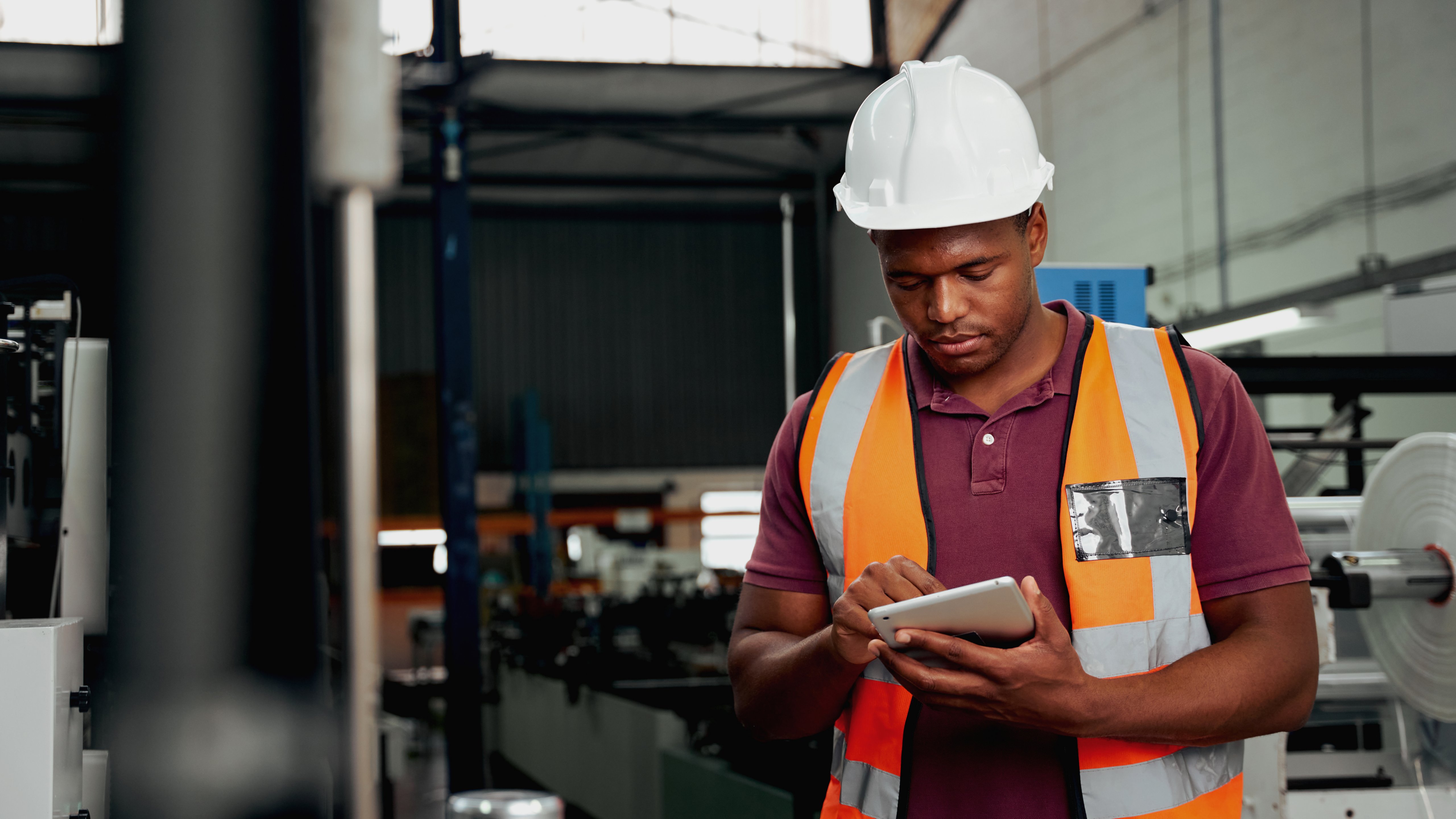 Engineer in white hard hat looking at tablet