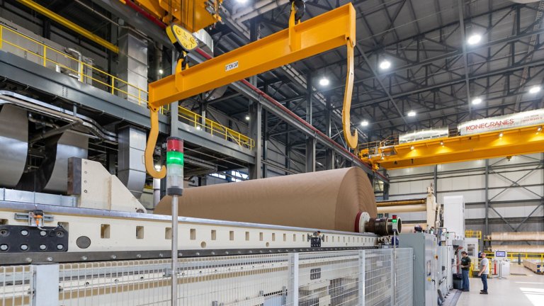 Inside a new paperboard mill, a overhead crane -- positioned by a PowerFlex drive -- moves a roll of new paper for processing and printing. 