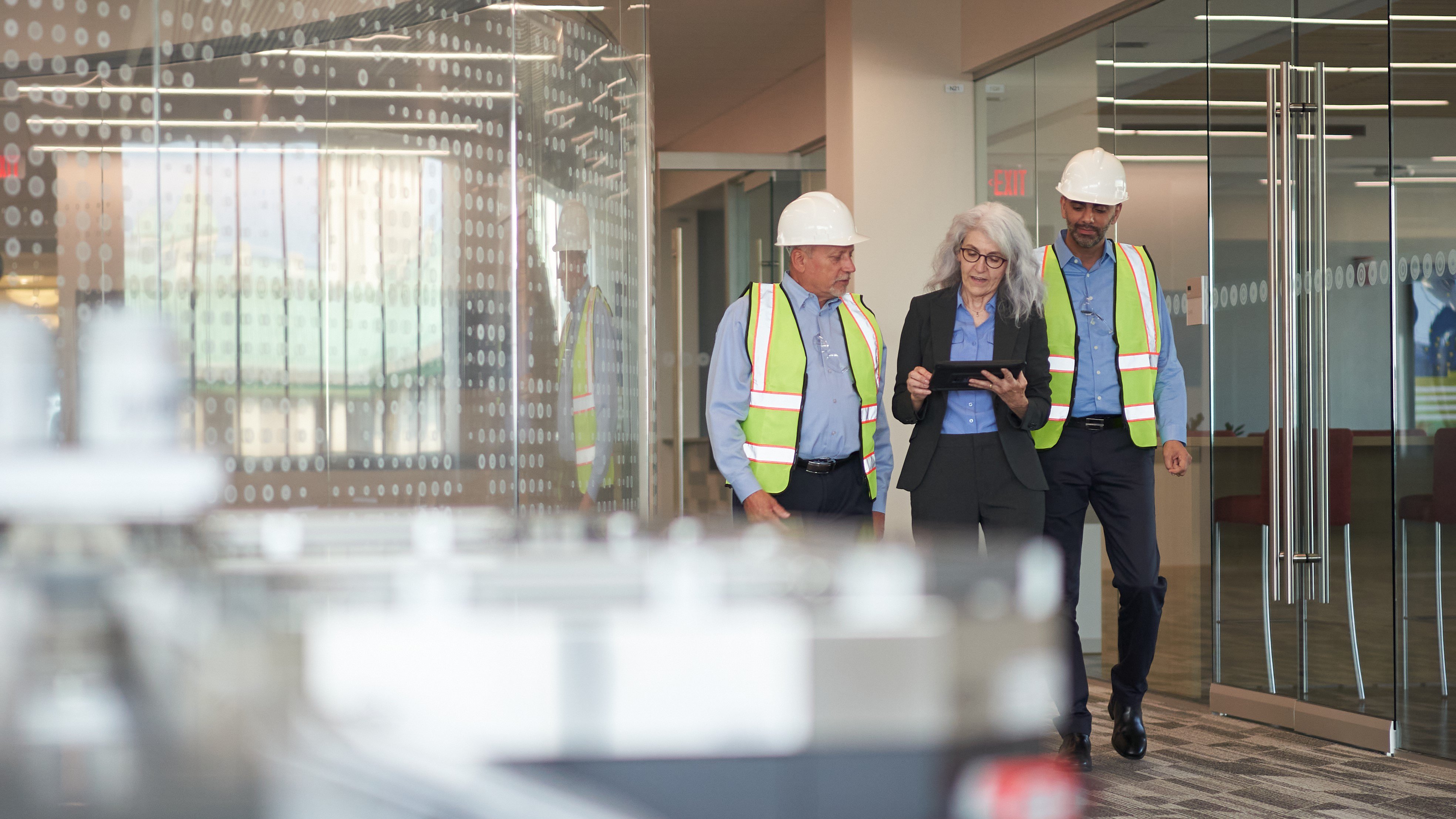 Two engineers and lady using tablet while walking through the company