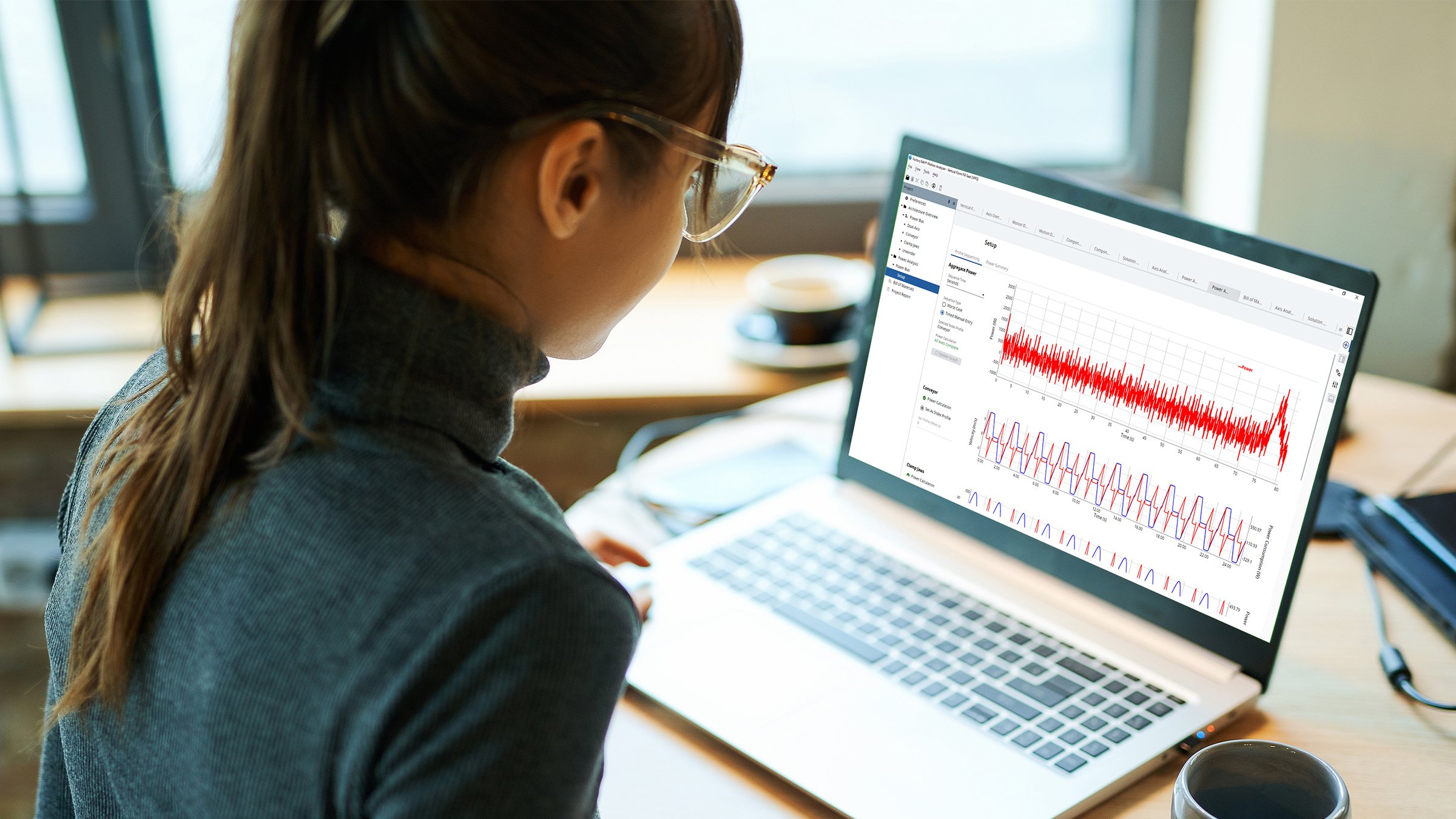 An over the shoulder view of a woman in a turtleneck sweater looking at her laptop that is displaying a FactoryTalk Motion Analyzer power analysis screen