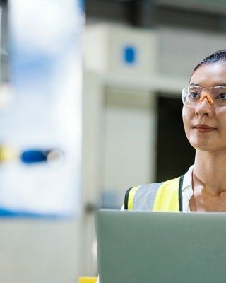 Female production engineer working on a laptop on the manufacturing plant floor