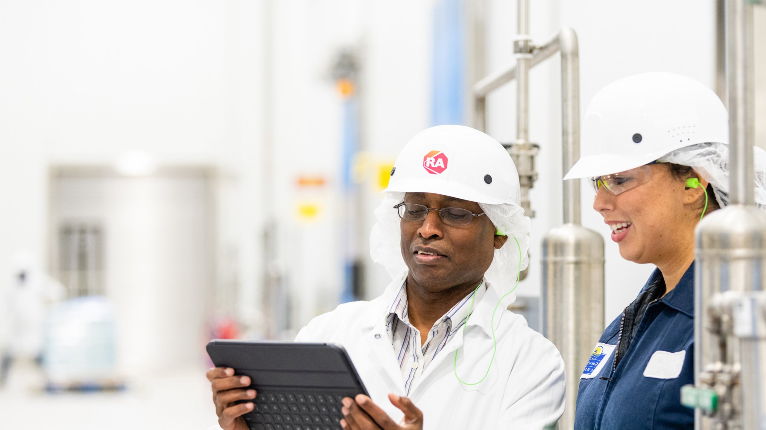 A female factory worker consults with a Rockwell Automation field service engineer on a modernization upgrade project.