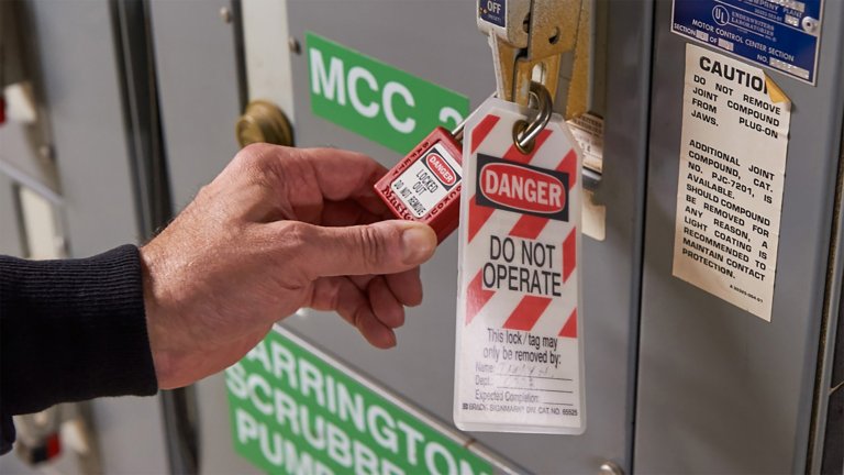 Electrical maintenance worker verifying lockout/tagout for an industrial electrical cabinet.