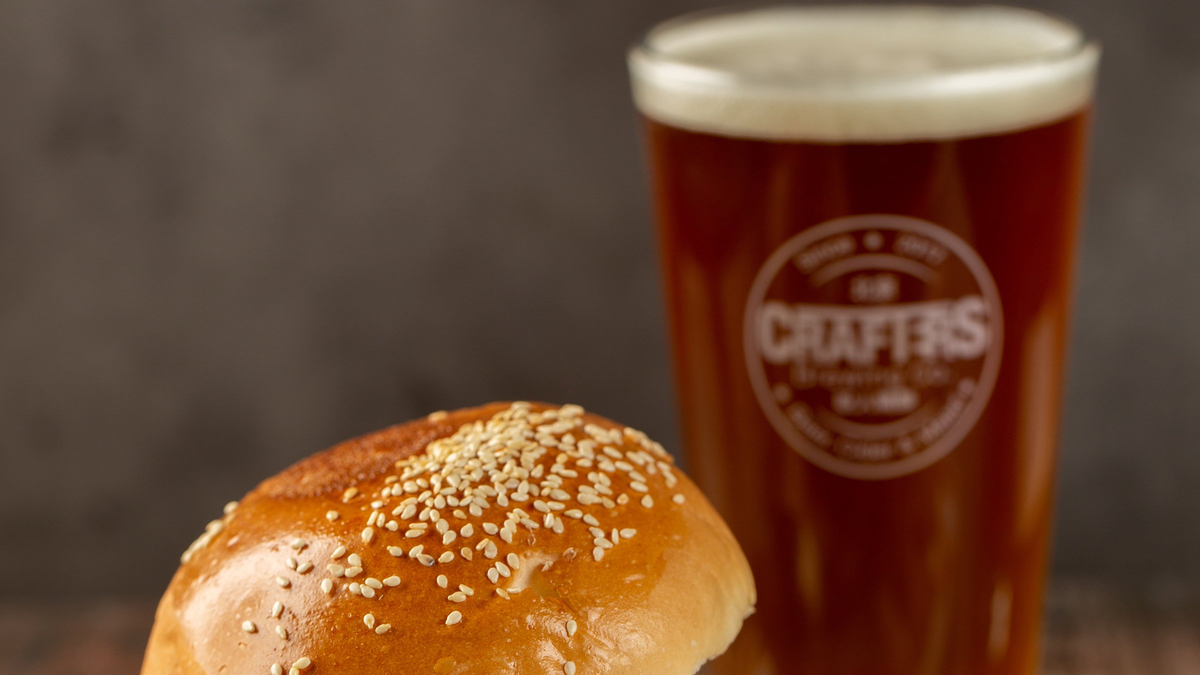 Glass of cold beer with hamburger and fries at a bar