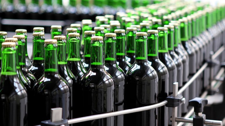 Green bottled beverages on a conveyor belt in a bottling plant.