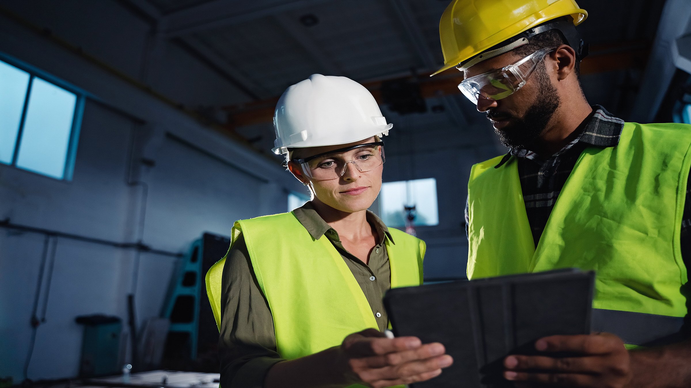 Inspectores industriales con una tablet haciendo un chequeo general y conversando en un taller industrial.