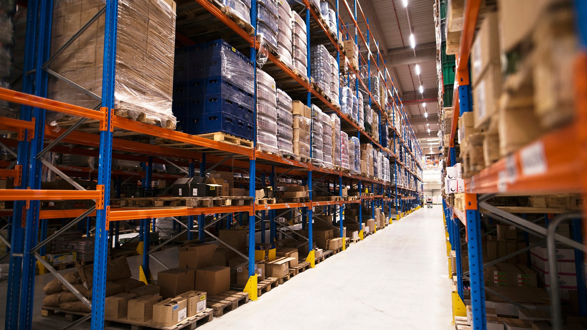 Interior of large distribution warehouse with shelves stacked with palettes and goods ready for the market.