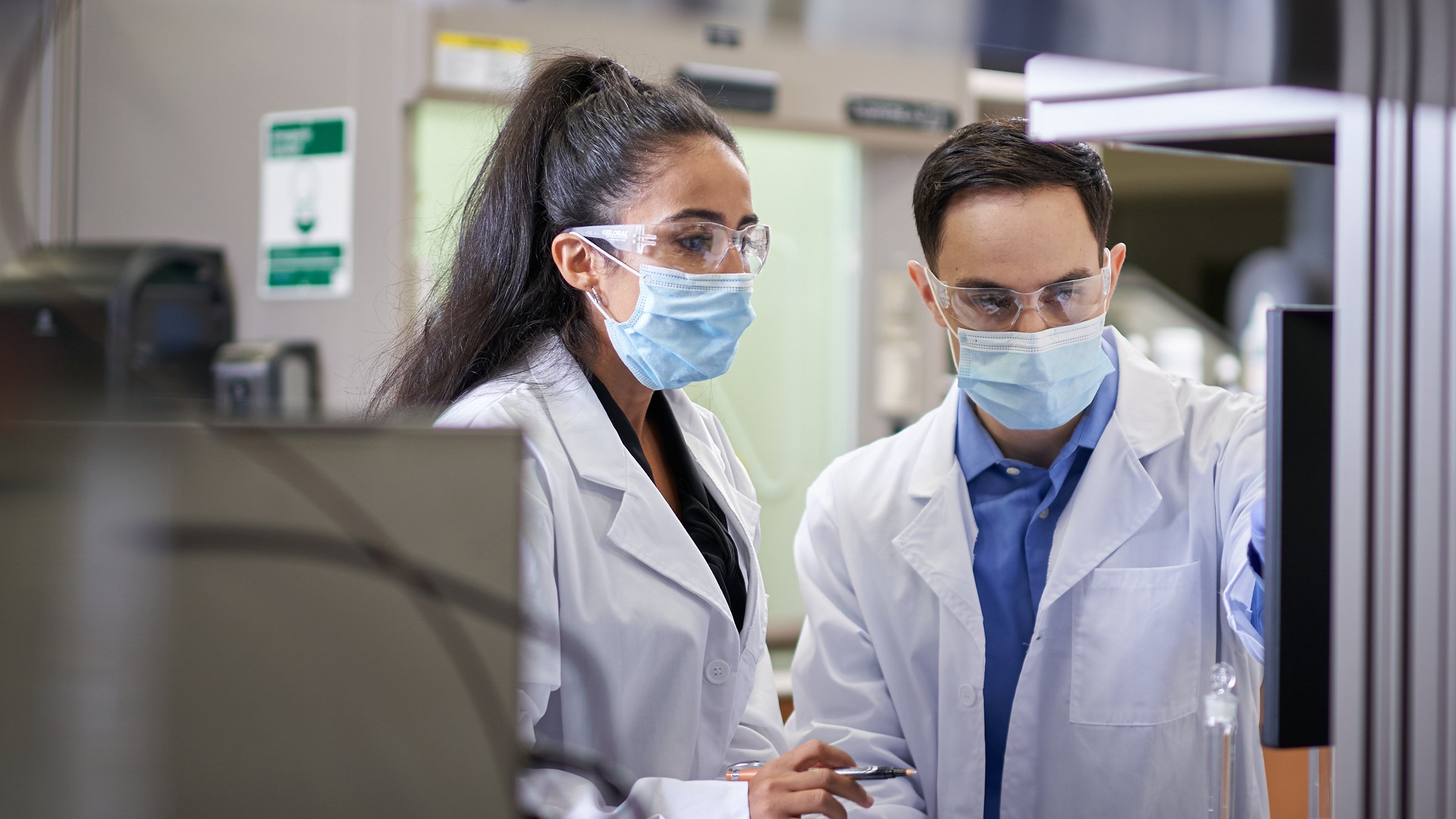 Two people waring protective gear and having a meeting in a laboratory