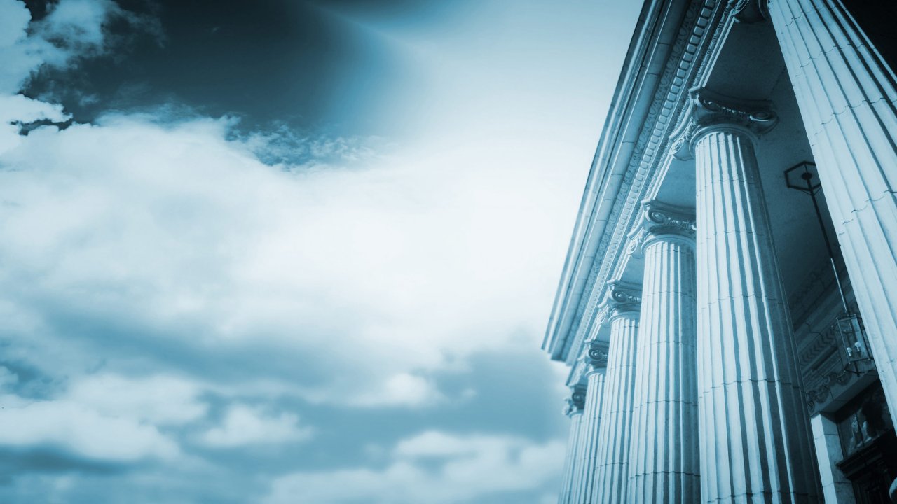 Abstract photo of building facade with greek columns and clouds in sky