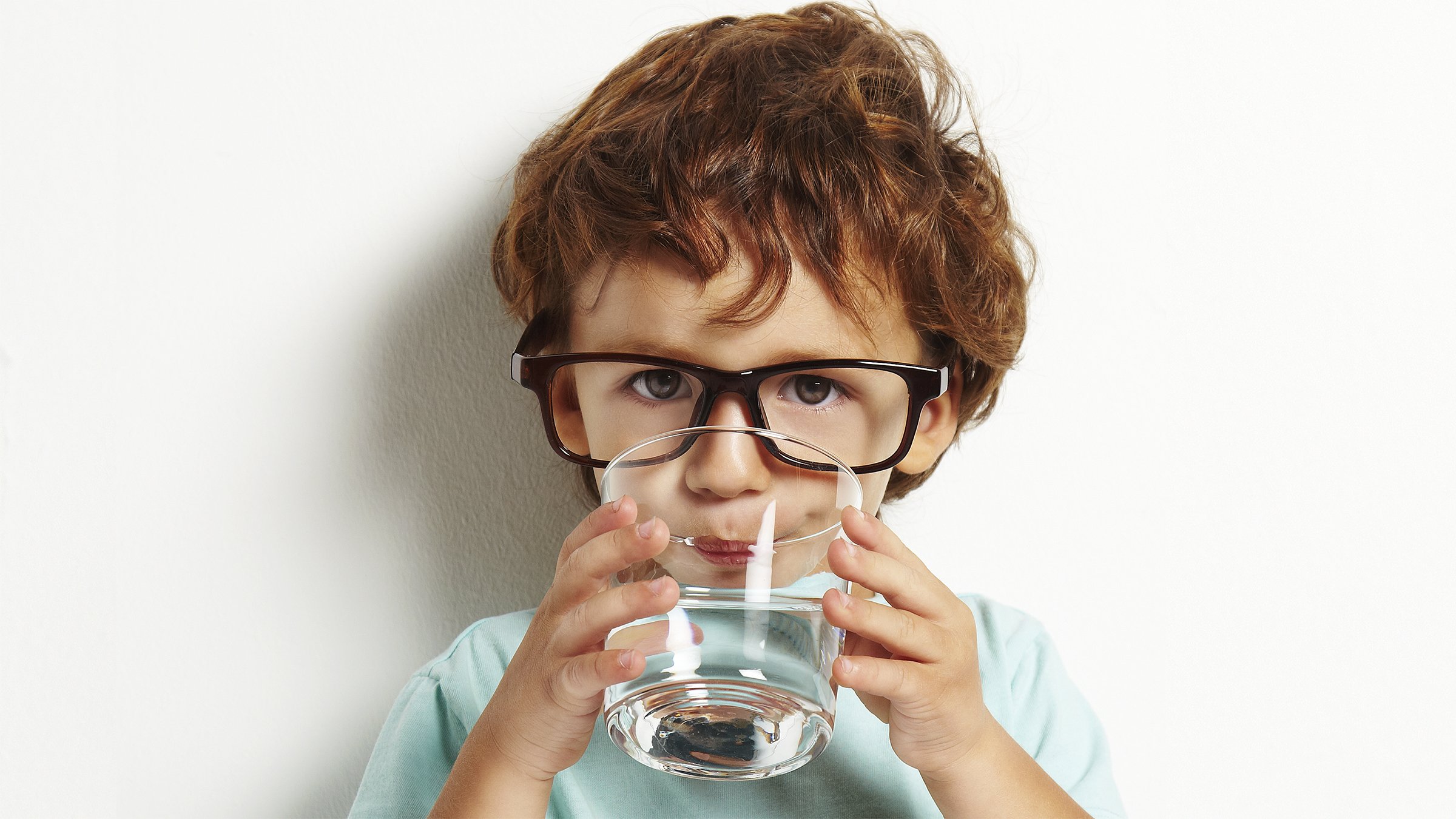 Little boy drinking from a glass of water