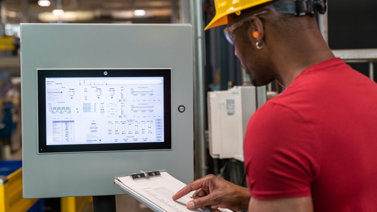 Male worker in Milwaukee brewery monitoring HDMI panel using Rockwell Automation software