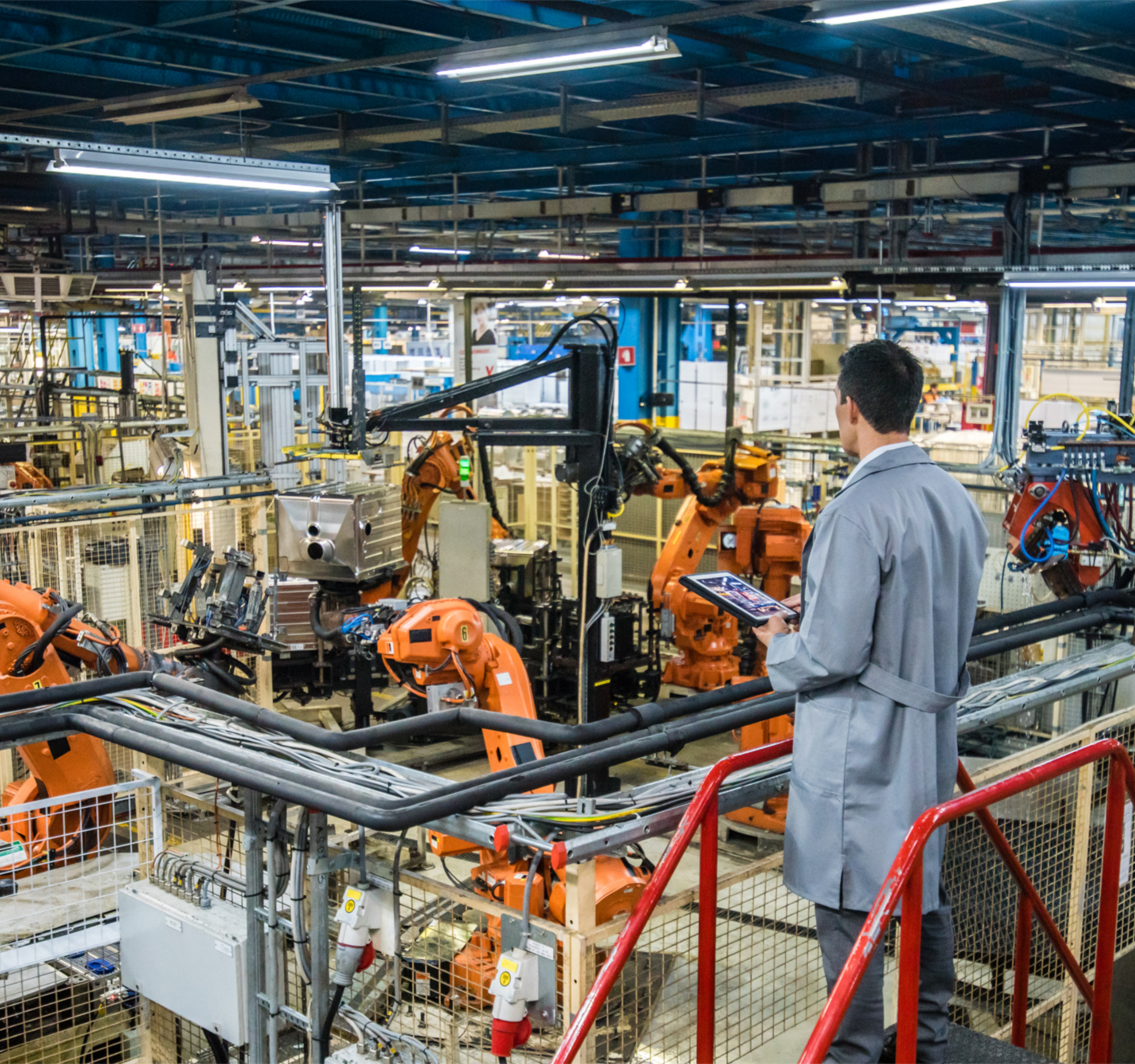 Male Worker Holding Tablet Overseeing Manufacturing Plant Floor.