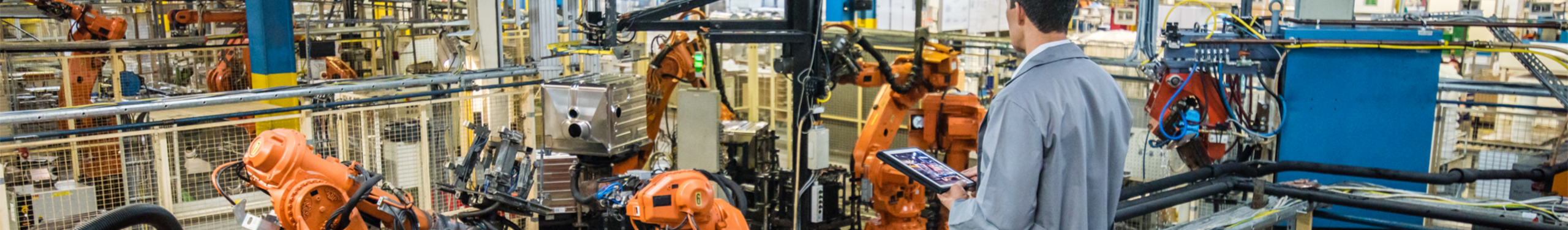 Male Worker Holding Tablet Overseeing Manufacturing Plant Floor.