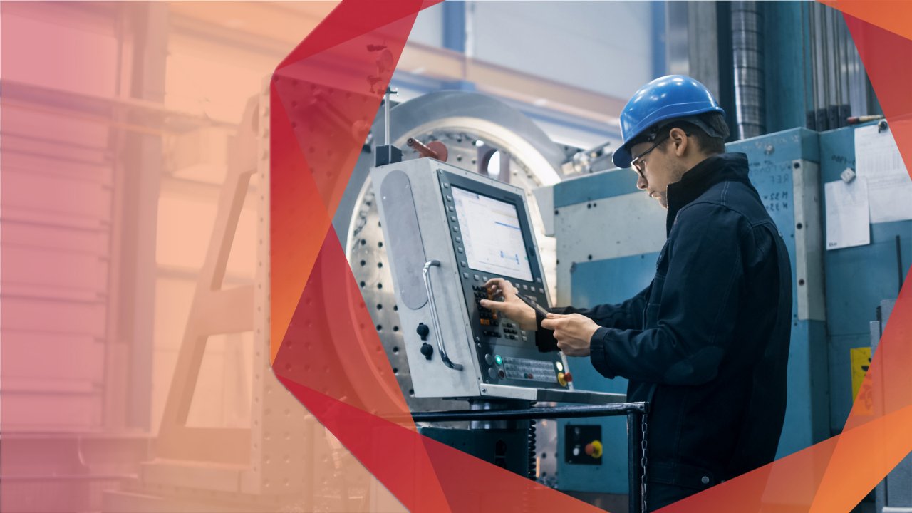 Un homme portant un casque de sécurité bleu tapant sur l’ordinateur d’une machine dans un environnement industriel.