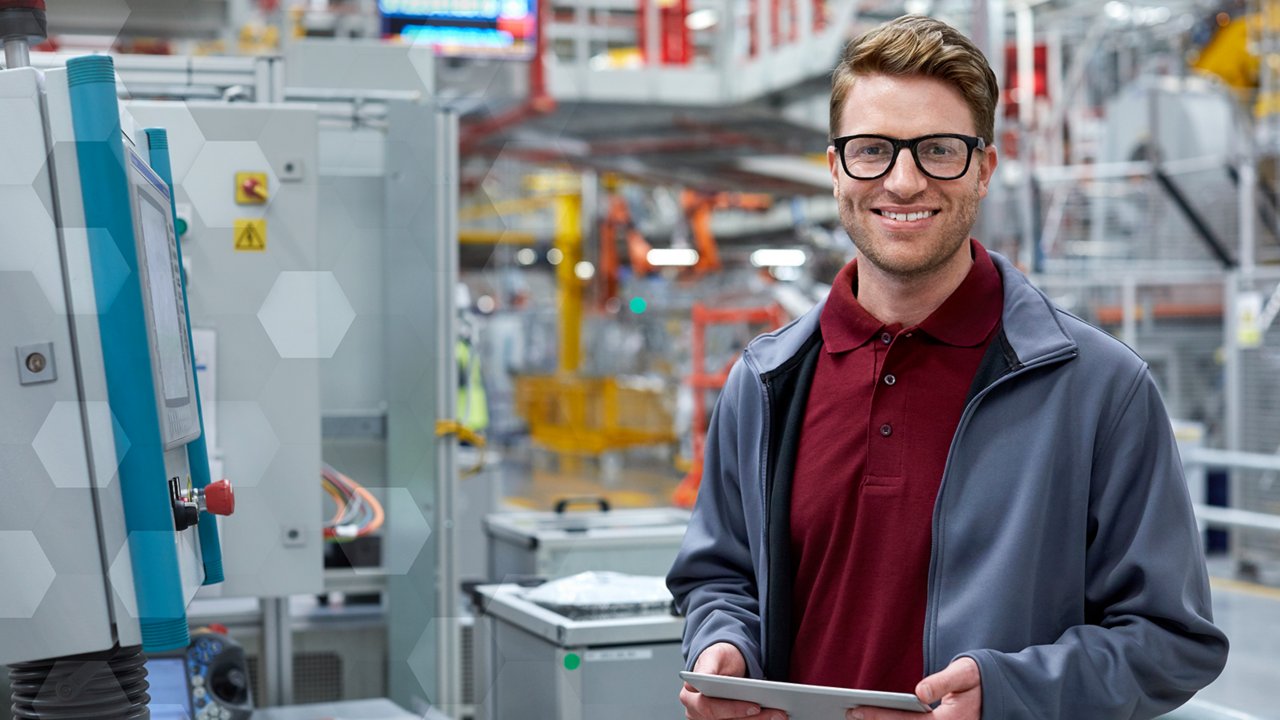 Hombre con anteojos, camiseta roja y chaqueta azul con una tableta en una fábrica implementando el programa de software de bloqueo-etiquetado ScanESC