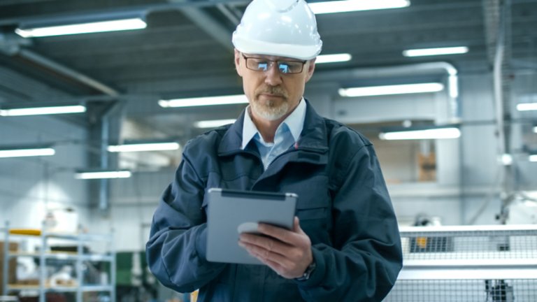 Factory worker in hard hat holding tablet