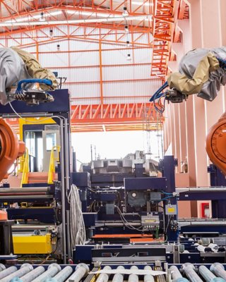 Two large orange robotic arms along manufacturing line networked cybersecurity