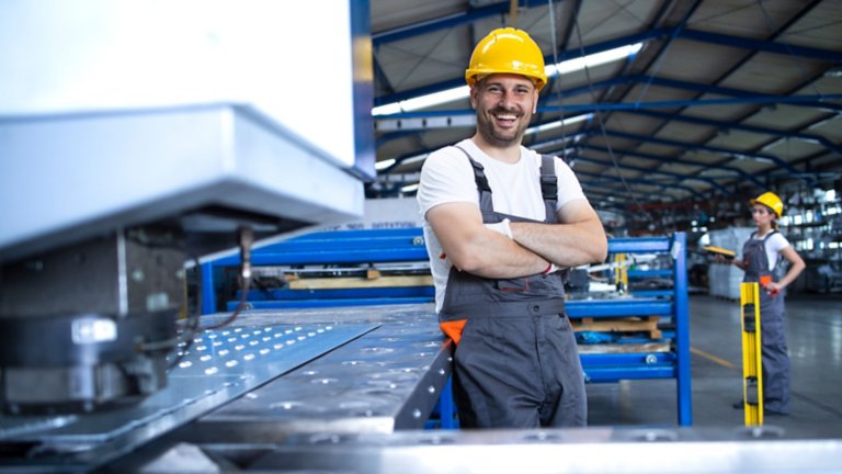 Trabajador sonriente con casco amarillo en planta industrial