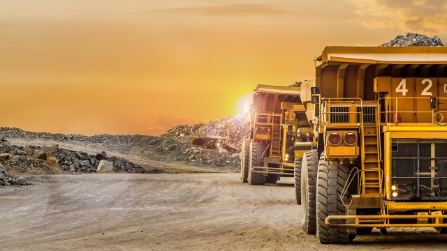 Grands camions-bennes jaunes transportant du minerai de platine pour traitement sur le site minier