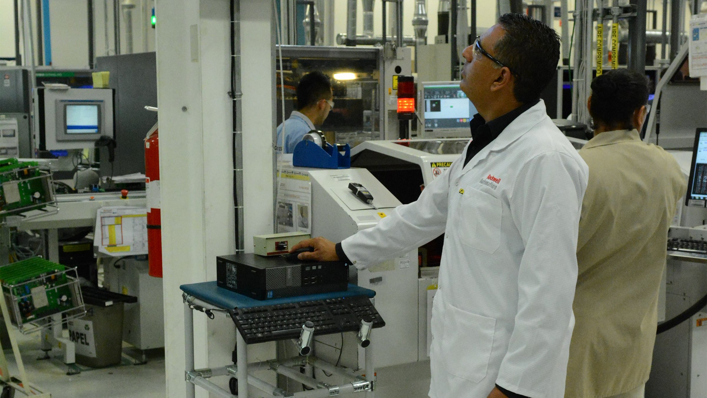 Engineer in white coat standing and looking at screen