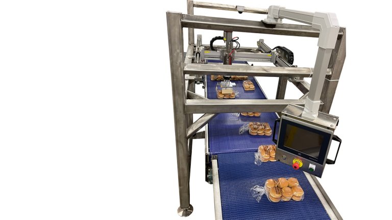 Sandwich buns enter the LeMatic P7 pattern former single file on a blue conveyor. An Allen-Bradley PanelView monitor is affixed above the conveyor.