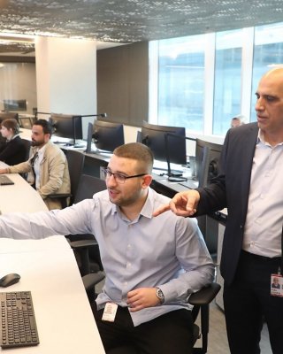 Ofek Lahiani points to his computer monitor while talking to Igal Cohen and Blake Moret in the Rockwell Automation Tel Aviv SOC.