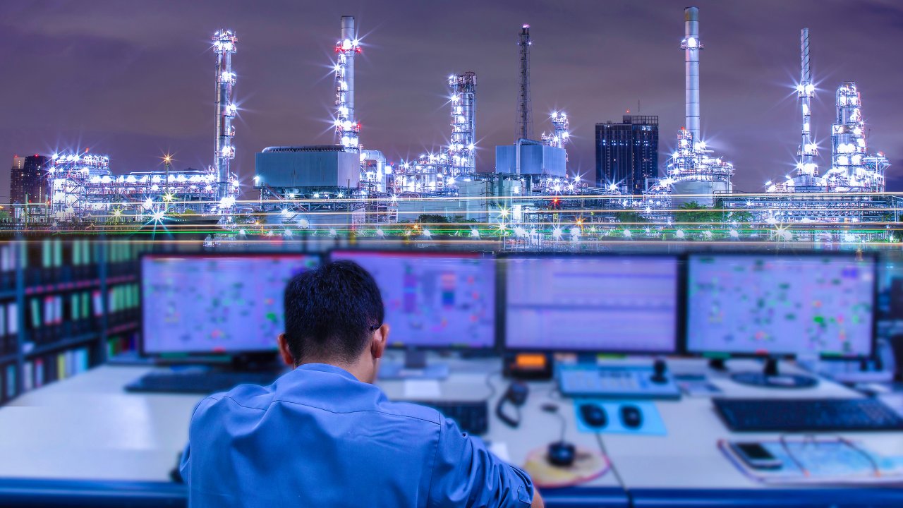 Ingenieros trabajan con una tableta en la sala de control de la producción de una refinería petrolera.