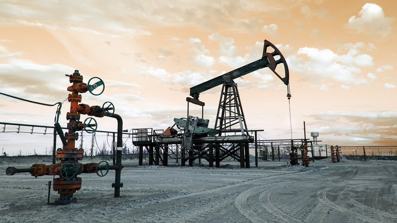  Close up of a working oilfield pumpjack platform and a wellhead on a hazy day