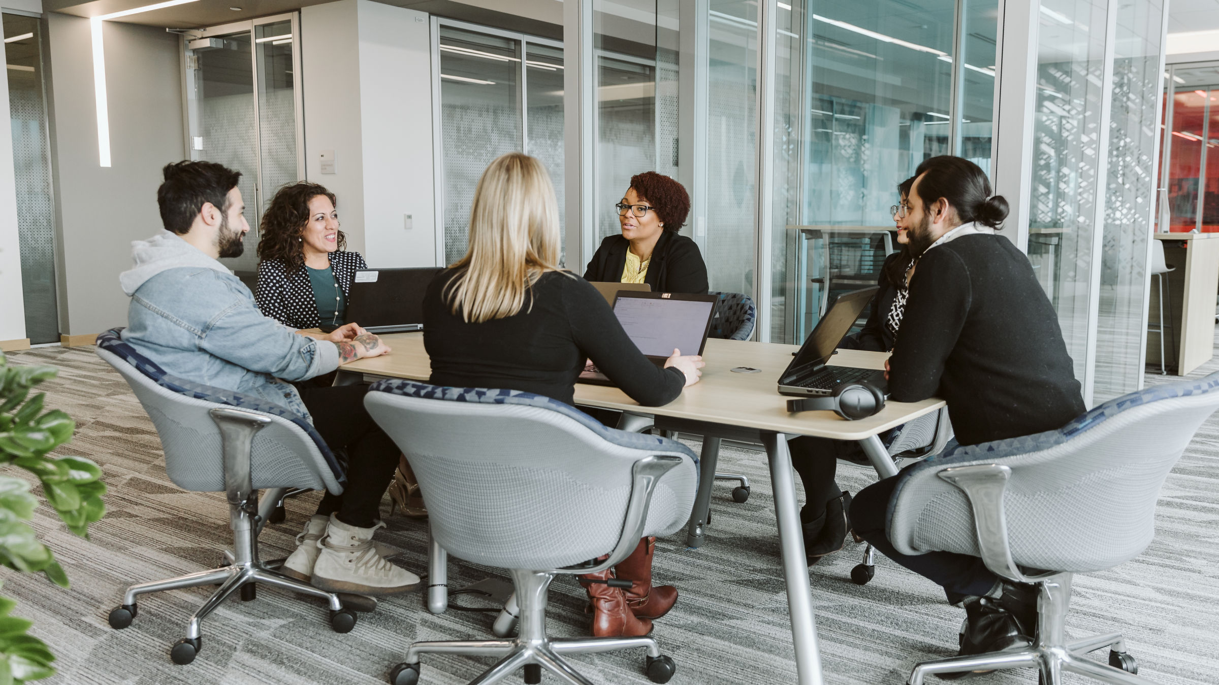 Group of people talking in a meeting and using laptops