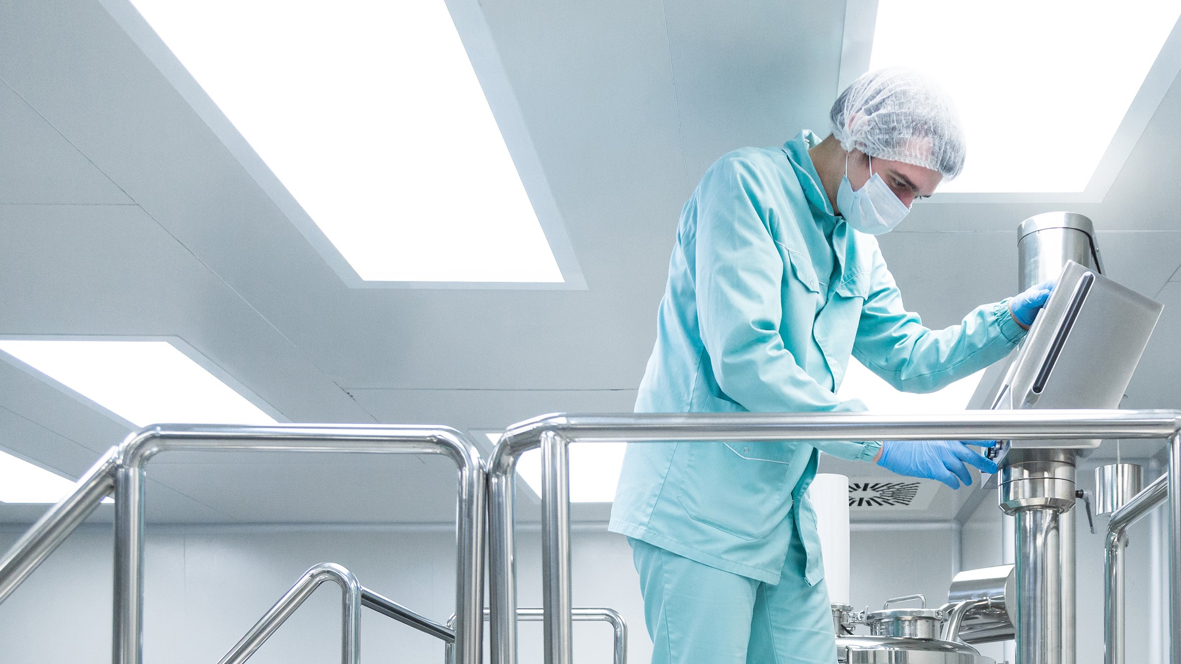 Pharmaceutical factory man worker in protective clothing operate production line in sterile working conditions