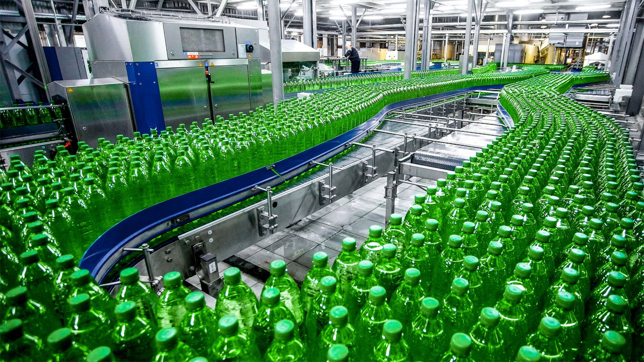 Garrafas de plástico verdes sobre um transportador em uma fábrica
