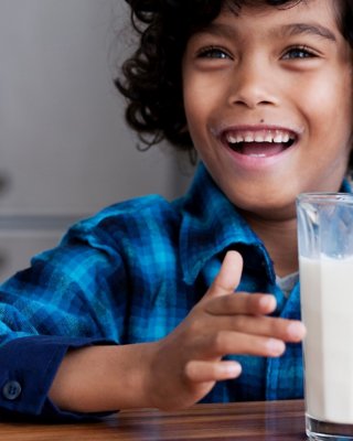  Smiling child sitting at a table with a glass of milk