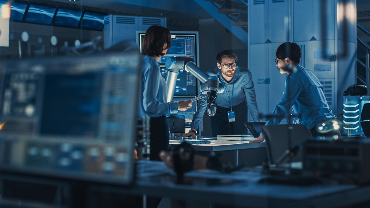 Equipo de ingenieros analiza un brazo robótico en una oficina con equipamiento moderno