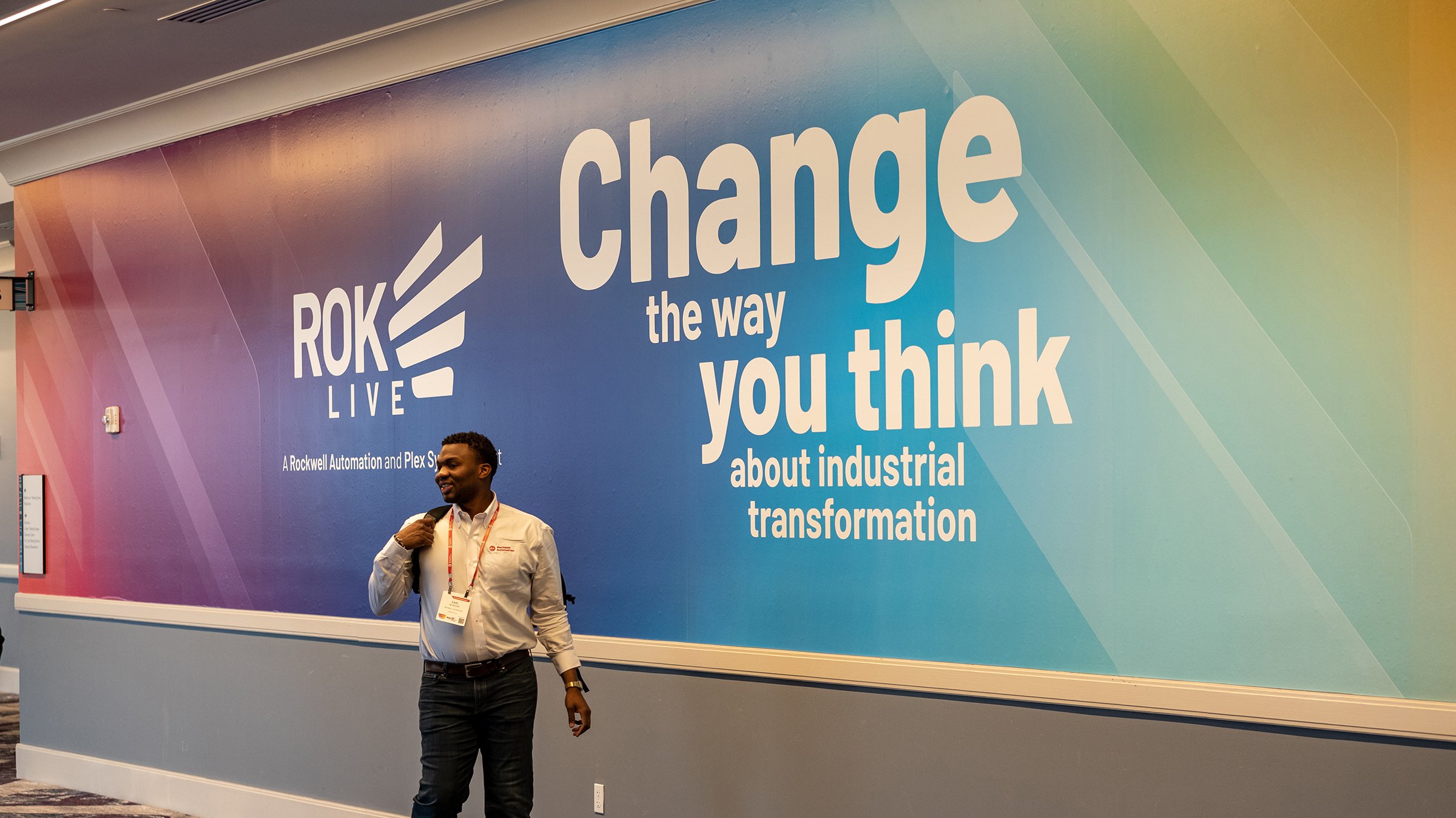 ROKLive attendee in front of Change the Way you think signage at show