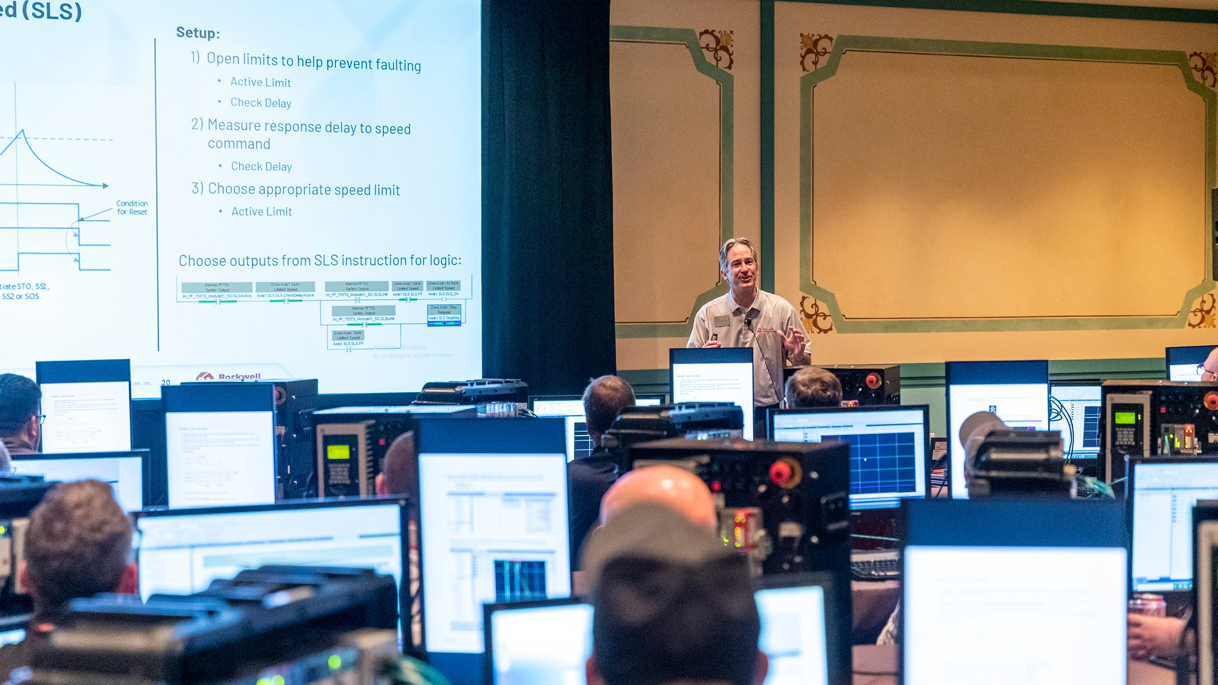 Speaker in front of multiple workstations and people learning about Rockwell Automation products at ROKLive