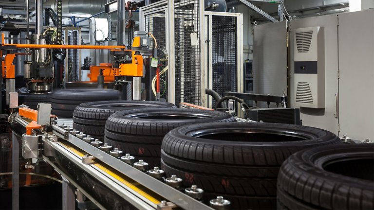 Em uma fábrica de pneus, os pneus descem por uma correia transportadora. A operação é aumentada com inversores de frequência inteligentes que controlam os motores durante todo o processo de fabricação