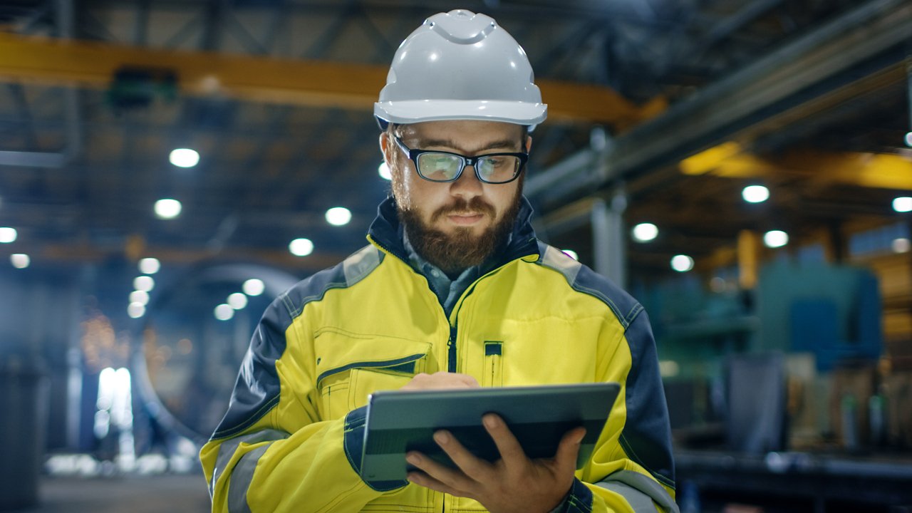 Industrial worker looking at machine data on tablet