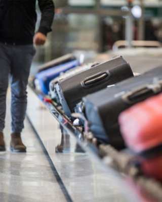 Two men carrying their luggage that was on a luggage conveyor at an airport terminal