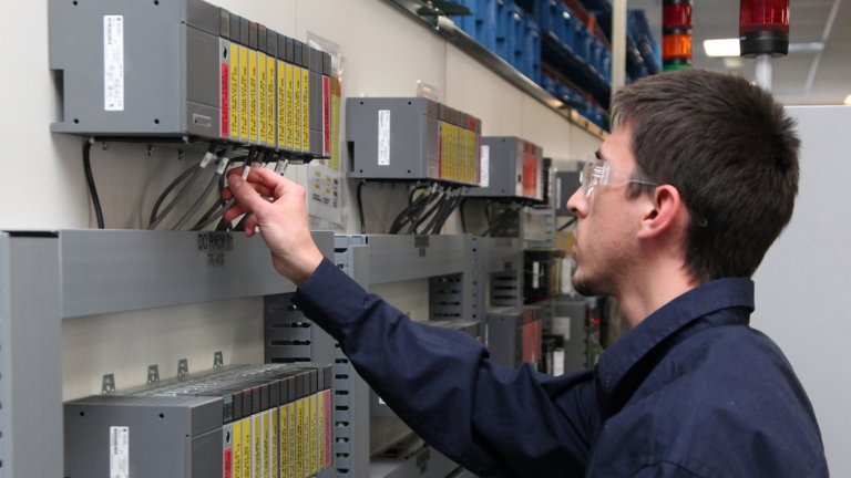 A male Rockwell Automation repair technician tests an Allen-Bradley SLC 500 control system to extend product life for the customer until they are ready to migrate to newer technology