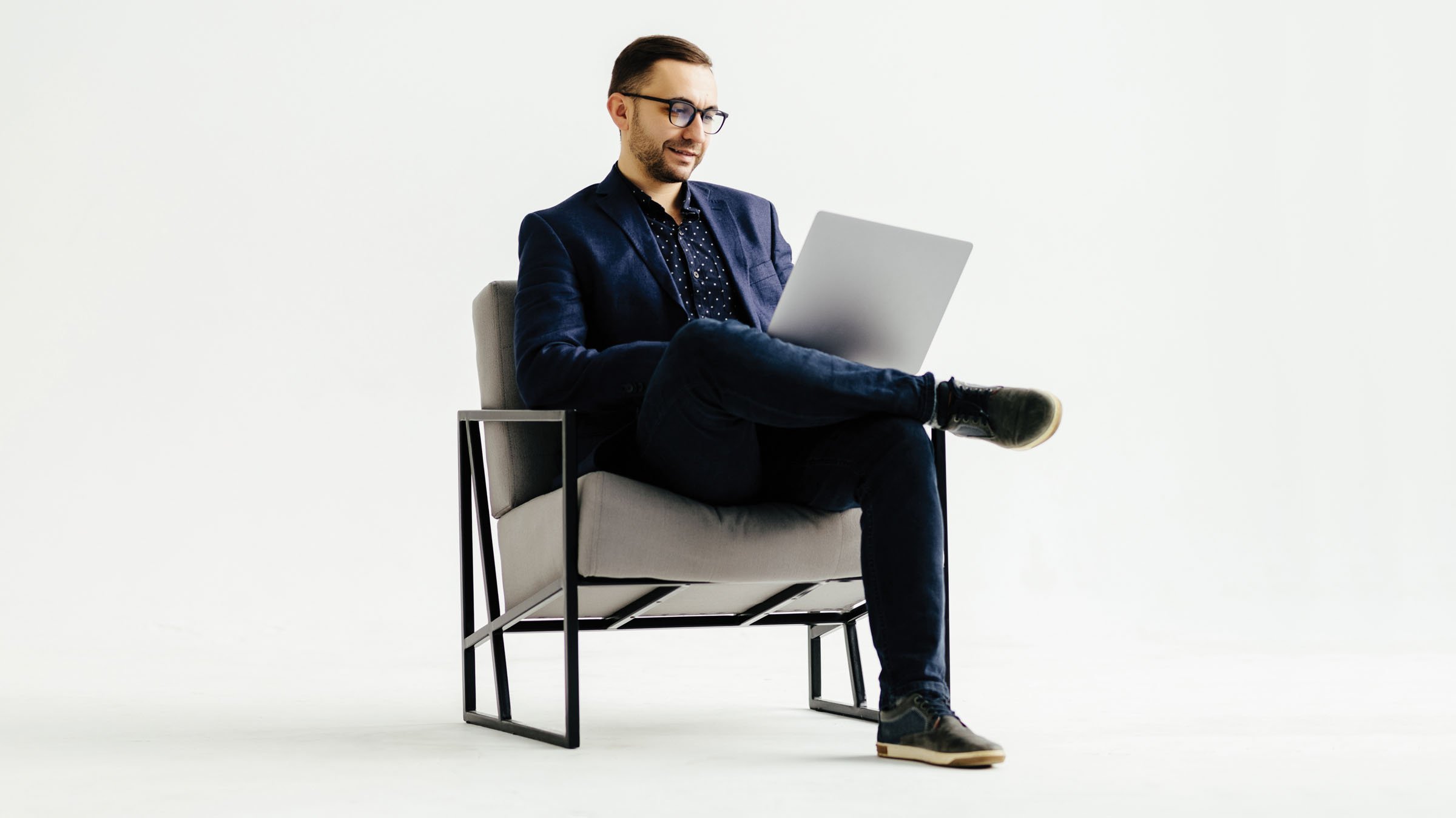 Smiling man using laptop sitting in chair.