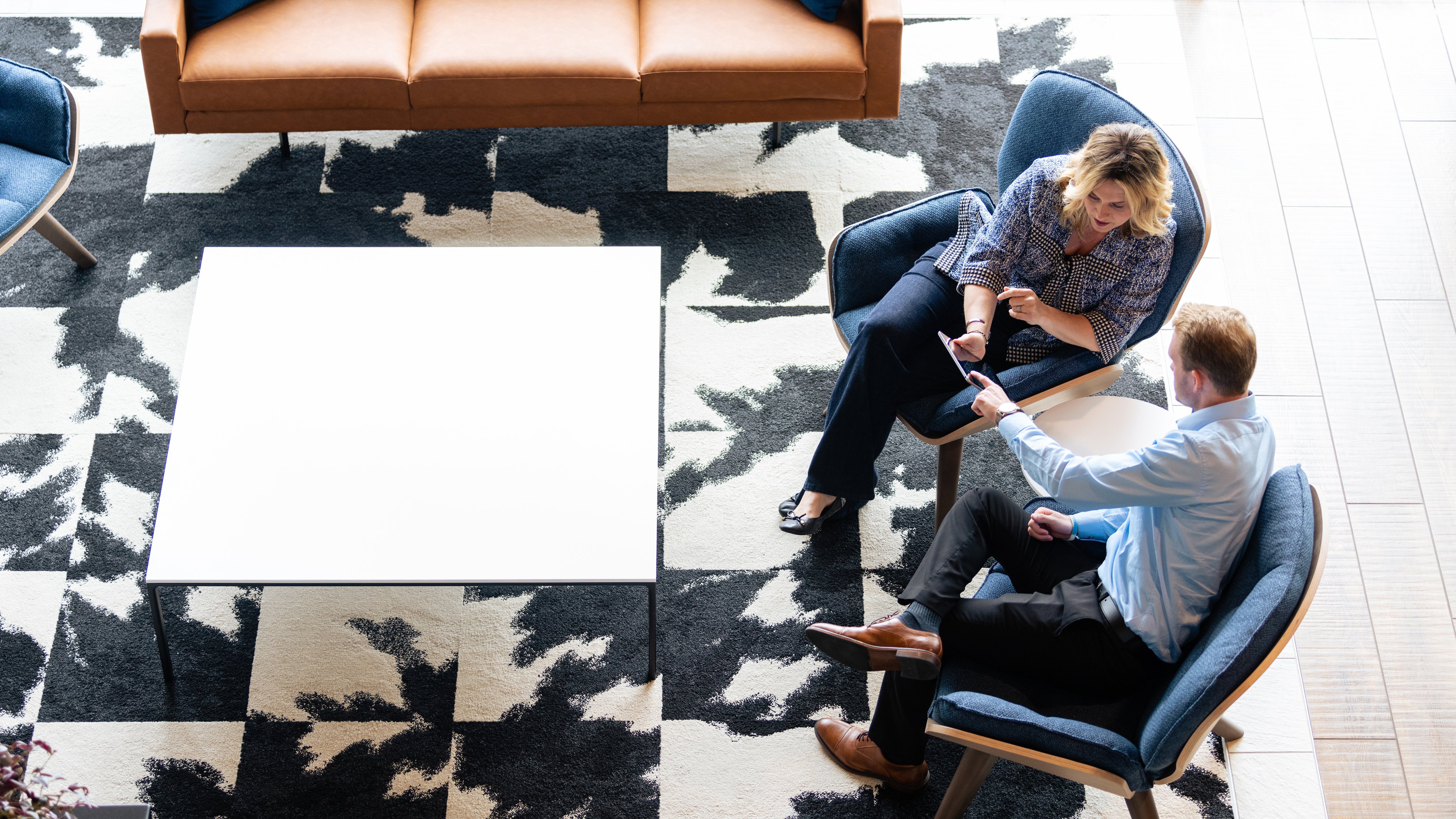 Male automation industry consultant shows tablet to female business professional while consulting on digital transformation.