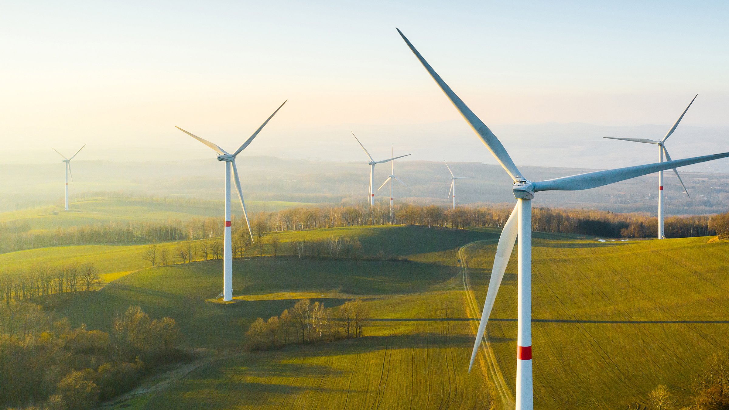 Close-up view of windmill with farm field in background during sunset