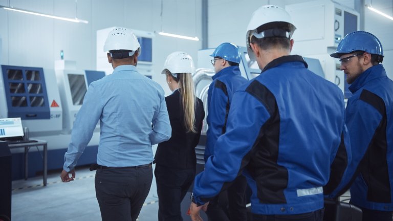 Female Chief Project Manager, Team of Engineers, Workers, Safety, Control Inspector Wearing Hardhats Walk Through Industrial Factory. Facility with Modern CNC Machinery. Side View