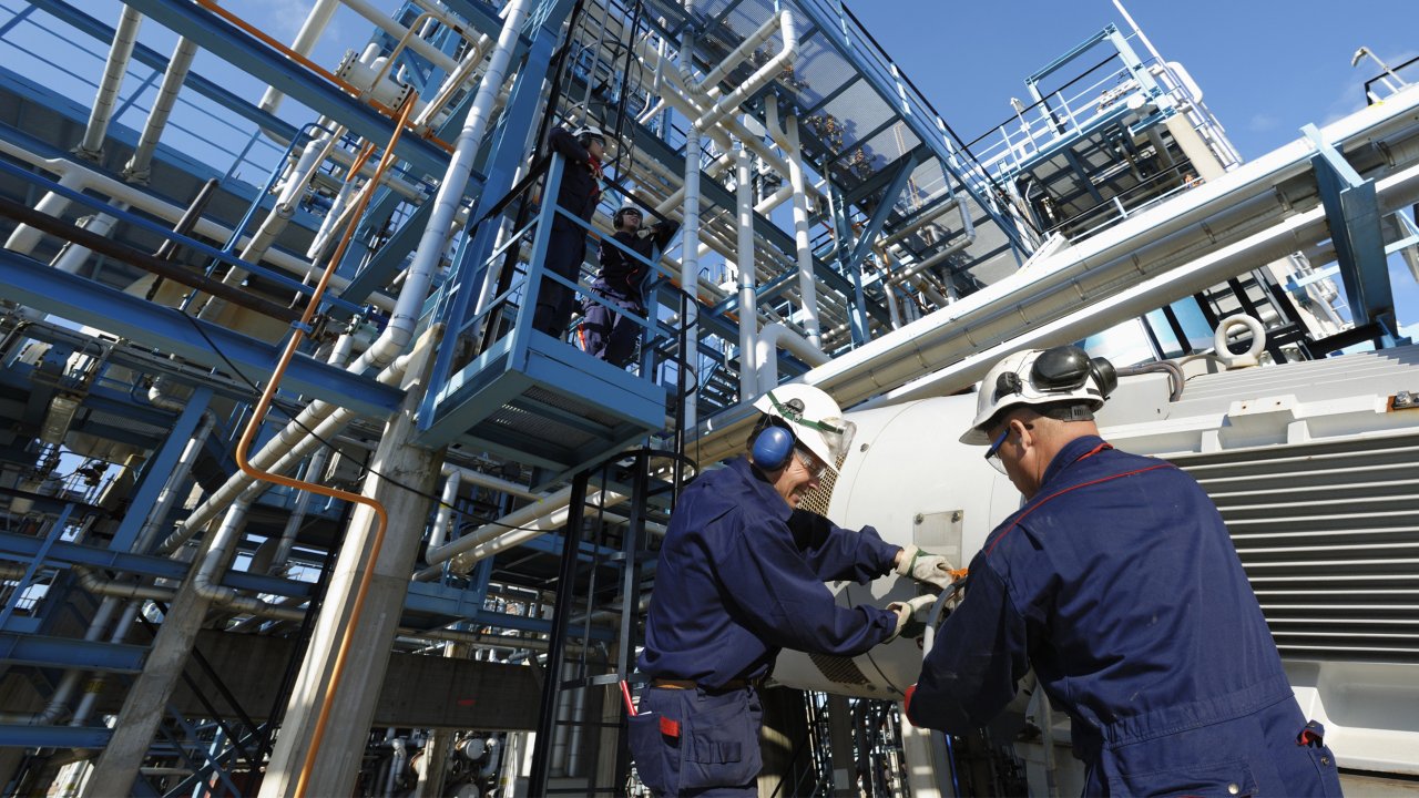 Ingénieurs travaillant dans une raffinerie, avec des pipelines et des zones de stockage