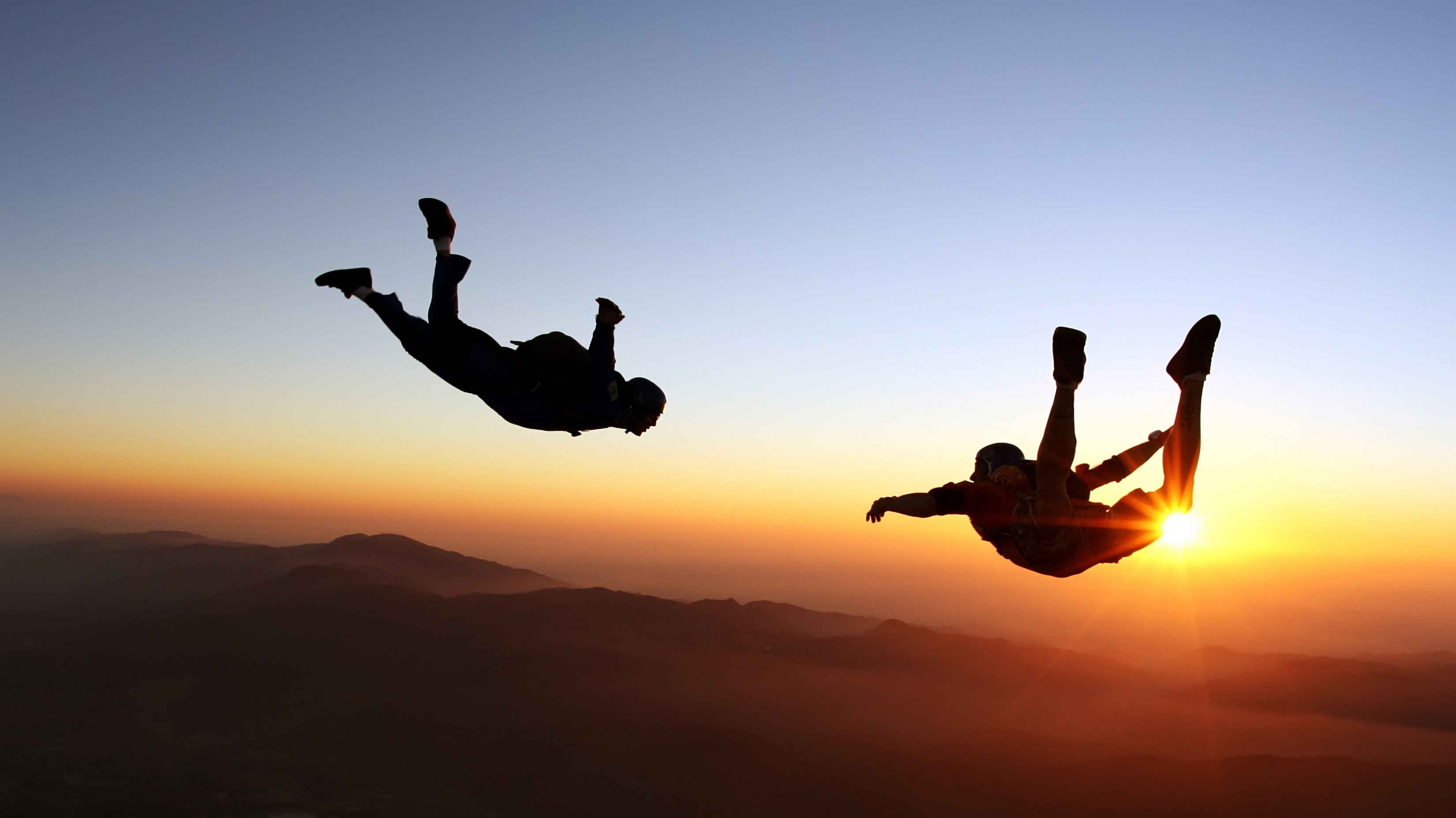 Two men skidiving in the sunset