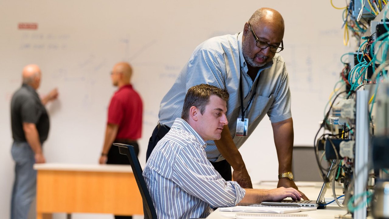 Two people working on a laptop using modbus