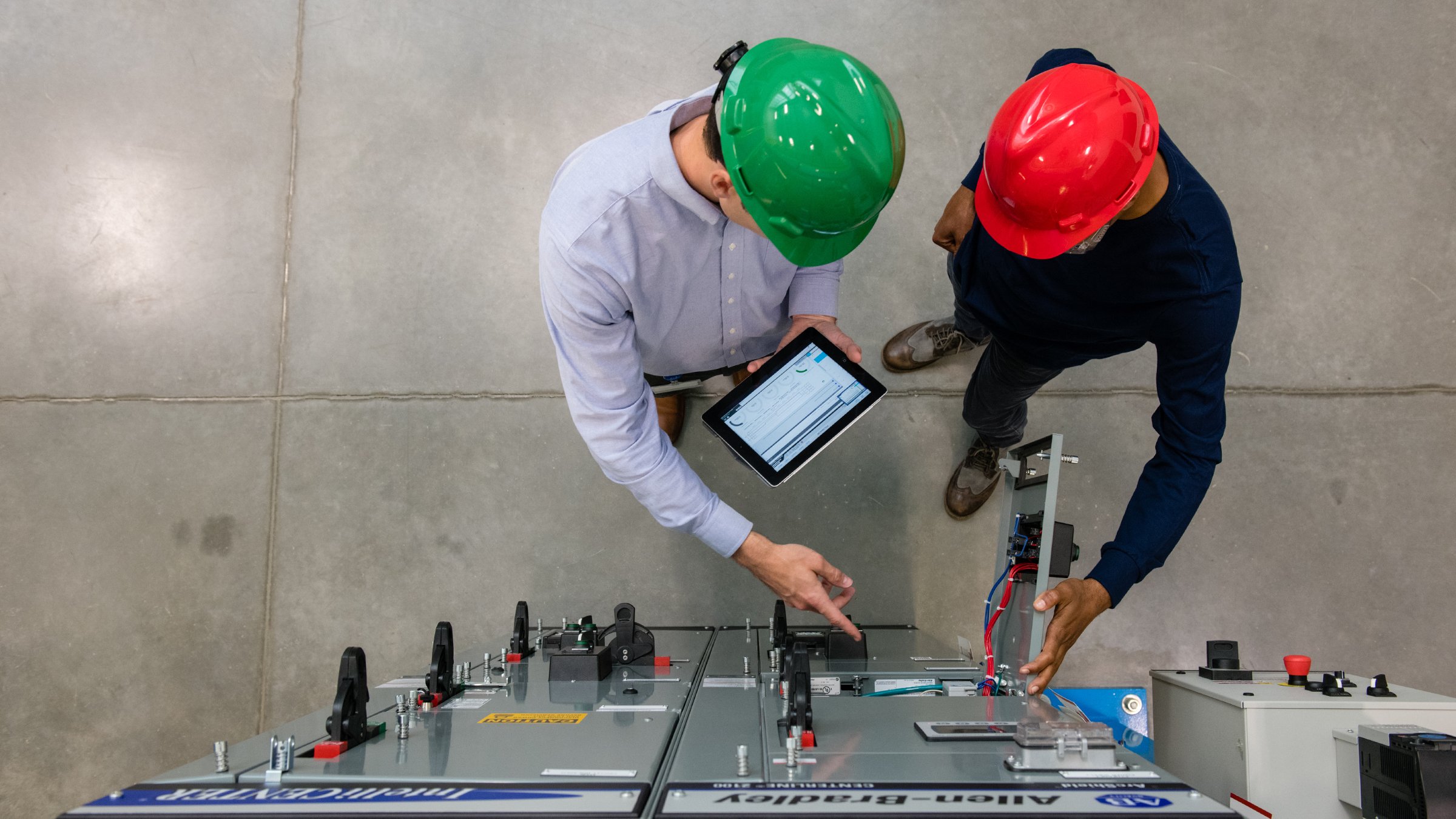 Two people working on a factory floor with a tablet