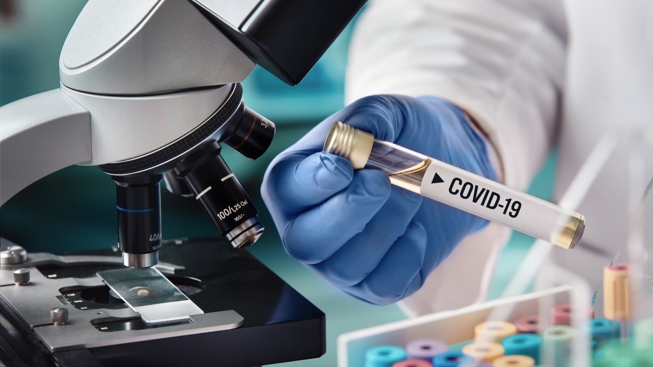 实验室里专员在显微镜下手拿一只疫苗试管。