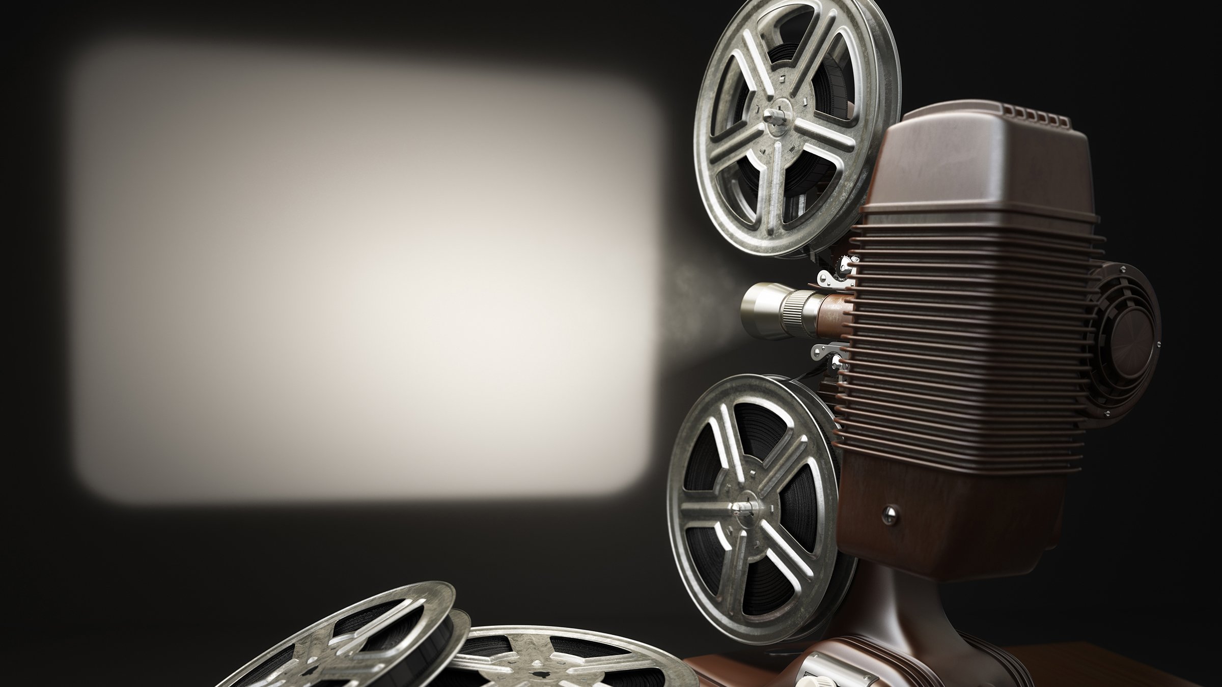 Vintage projector with reels of film in old-time theater projecting blank screen, black and white.