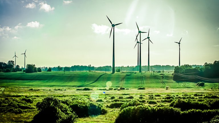 Wind power turbines in a green grass field.